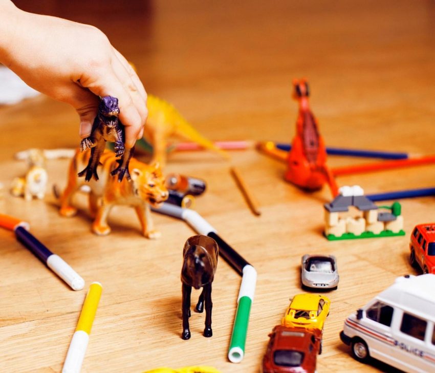 Small figurines, mini cars and colouring markers spread on a table, perfect compact toys for family trips